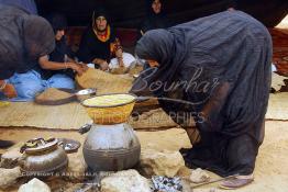 Image du Maroc Professionnelle de  Sous une tente bédouine plusieurs femmes du Sahara  préparent le couscous durant le grand Moussem de Tan Tan, classé en 2005 patrimoine immatériel humain mondial de l'Unesco. Le Moussem est une sorte de foire annuelle, à la fois économique, culturelle et sociale. Chaque année la majorité des tribus et des grandes familles nomades du désert se retrouvent sur un site désertique "Place de la Tolérance et de la Paix " à la périphérie de Tan Tan où  danse, chants, course de chameaux et fantasia font partie des festivités. , Samedi 18 septembre 2004, ((Photo / Abdeljalil Bounhar) 